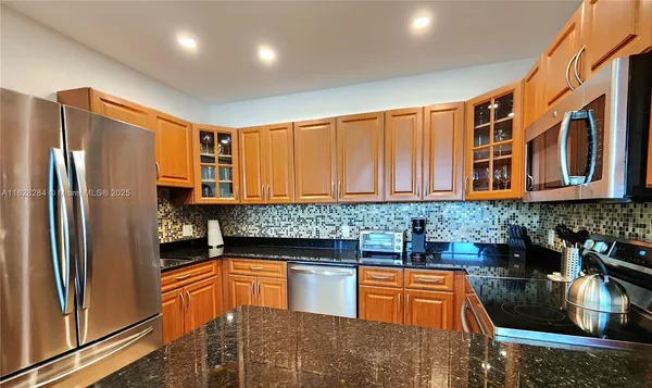 a kitchen with stainless steel appliances granite countertop a refrigerator a stove and a sink