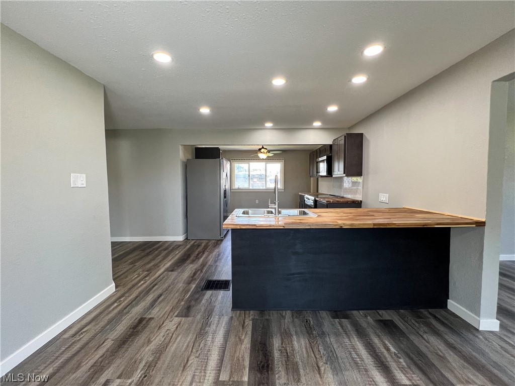 602 West Marshall Road McDonald, OH 44437 - Photo 10 of 19 Kitchen with sink, dark hardwood floors, butcher block counters, ceiling fan, and stainless steel appliances
