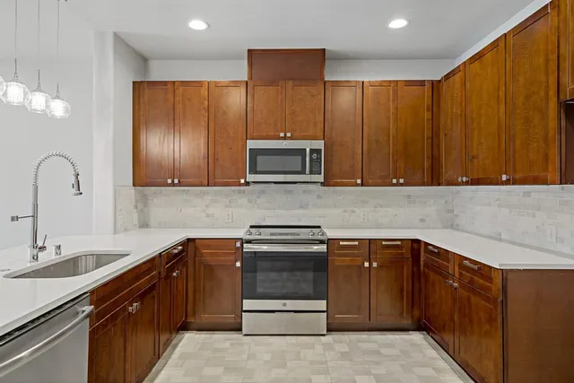 a kitchen with stainless steel appliances granite countertop wooden cabinets a sink and dishwasher
