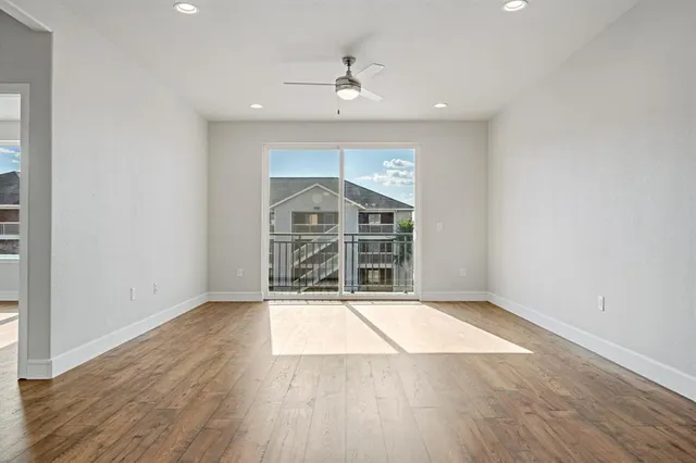 an empty room with wooden floor a ceiling fan and windows