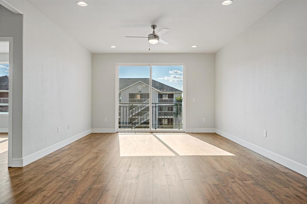 1220 West Trinity Mills Road, Unit 2011 Carrollton, TX 75006 - Photo 4 of 13 an empty room with wooden floor a ceiling fan and windows