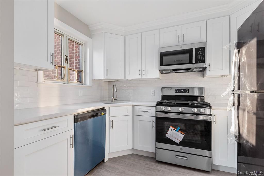 220-06 Stronghurst Avenue, Unit UPPR Queens, NY 11427 - Photo 9 of 12 a kitchen with stainless steel appliances a stove microwave and sink