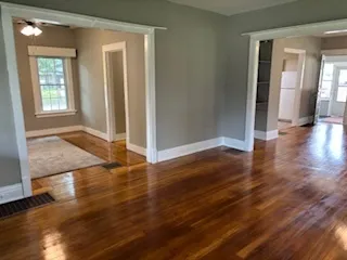 an empty room with wooden floor and windows