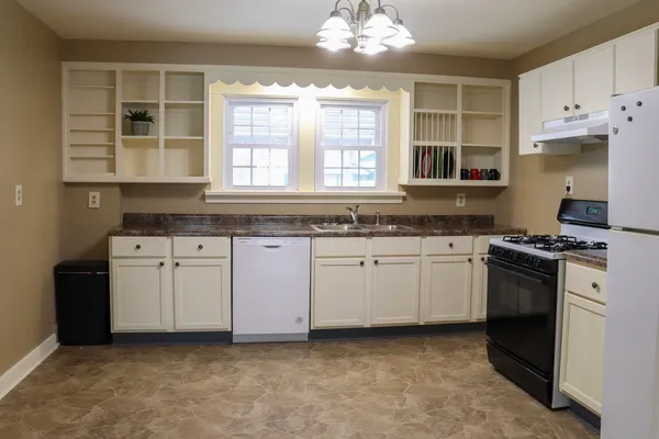 a kitchen with granite countertop a stove a sink dishwasher and a refrigerator