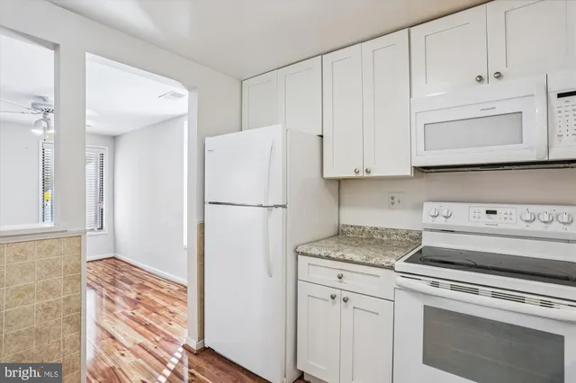 a kitchen with granite countertop white cabinets and white appliances