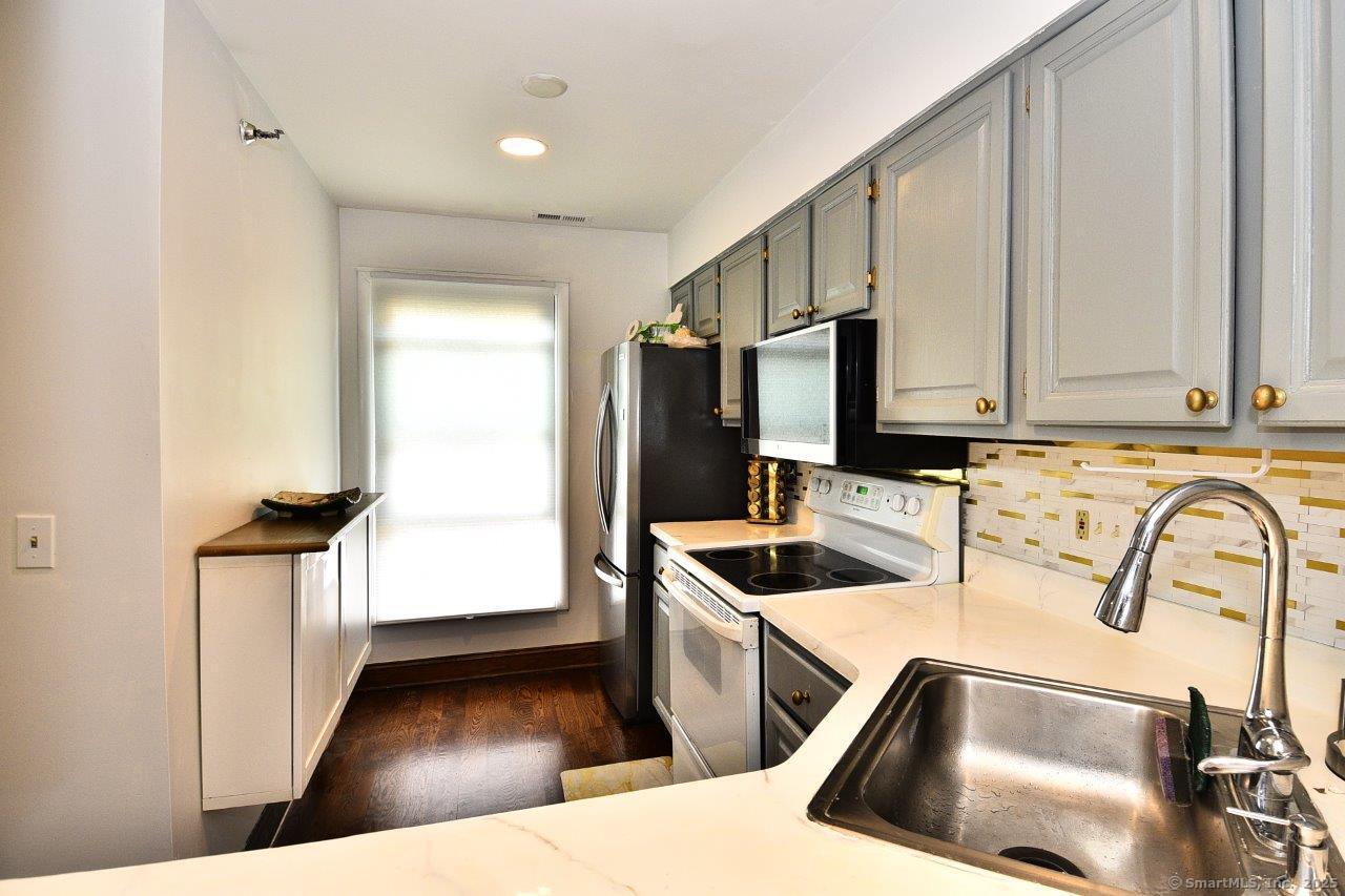 178 Flax Hill Road, Unit C203 Norwalk, CT 06854 - Photo 8 of 35 a kitchen with stainless steel appliances granite countertop a sink a stove and a refrigerator with wooden floor