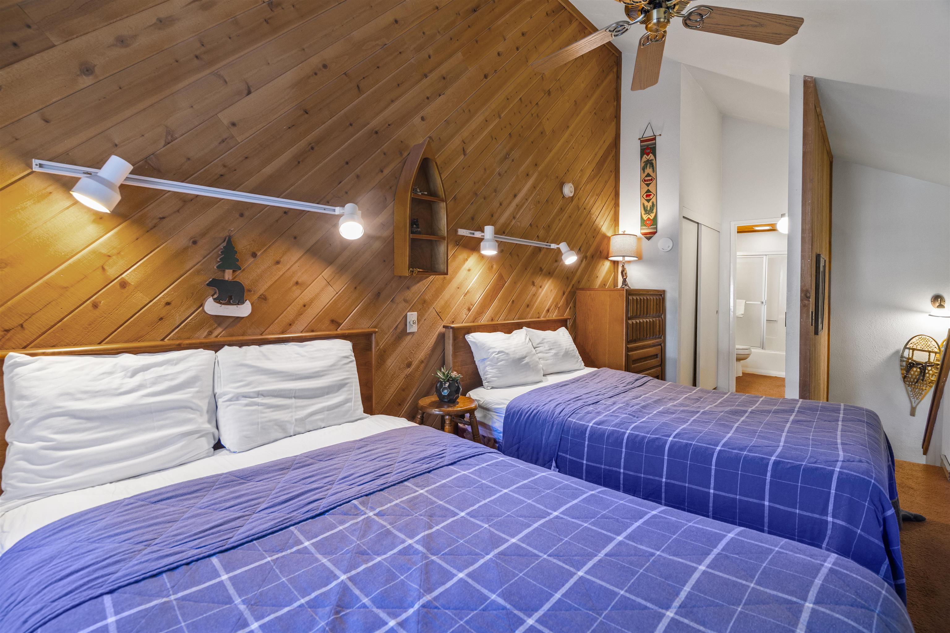 153 Lake Mary Road, Unit 114 Mammoth Lakes, CA 93546 - Photo 14 of 22 Sloped wood-paneled accent wall with track lighting, dual ceiling-mounted fan fixture, built-in shelving, and wood-finish flooring