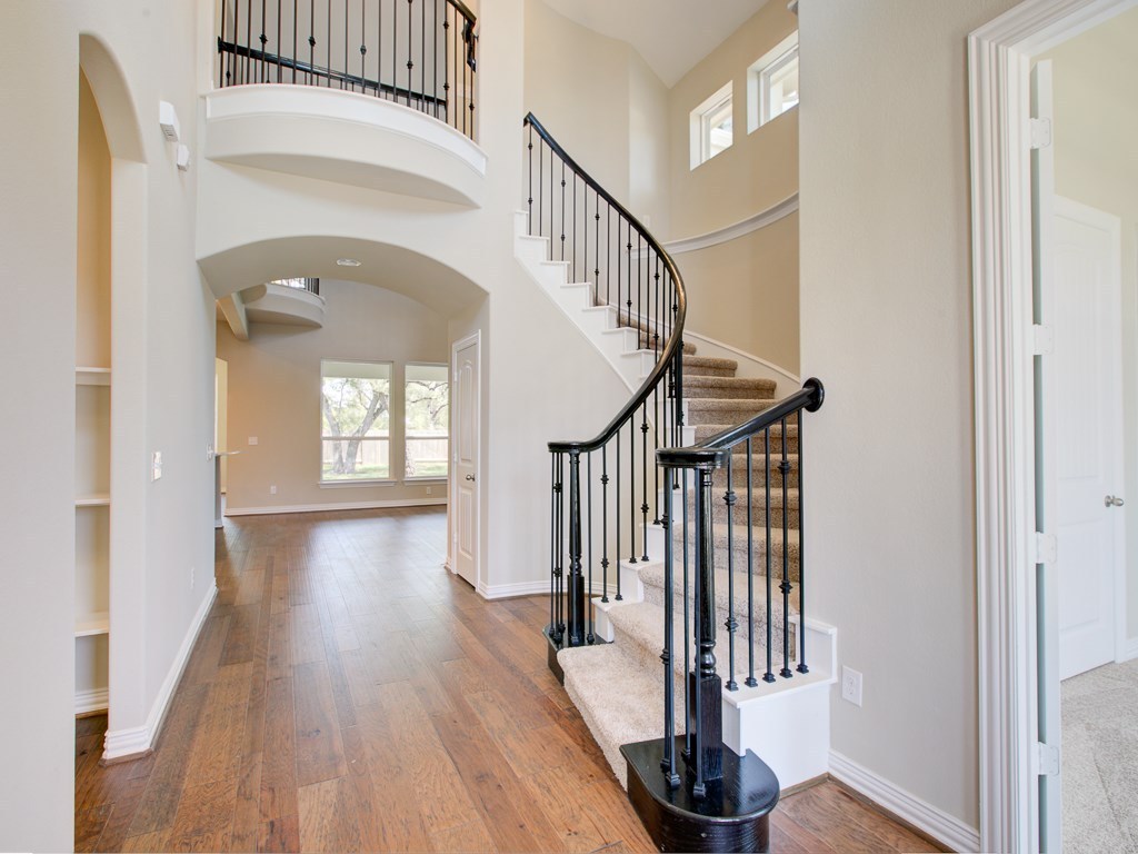 4303 Logan Ridge Drive Cedar Park, TX 78613 - Photo 7 of 24 Grand foyer featuring a curved staircase with wrought iron balusters and carpeted treads