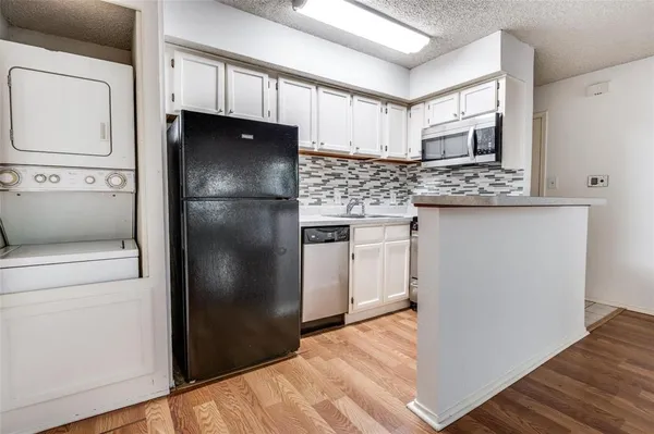 a kitchen with stainless steel appliances granite countertop a refrigerator a stove and a sink with wooden floor