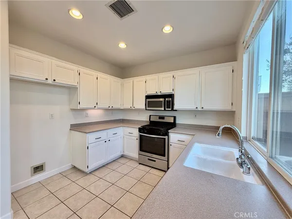 a kitchen with granite countertop white cabinets and stainless steel appliances