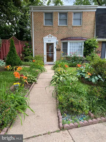 a view of a brick house with a yard and plants