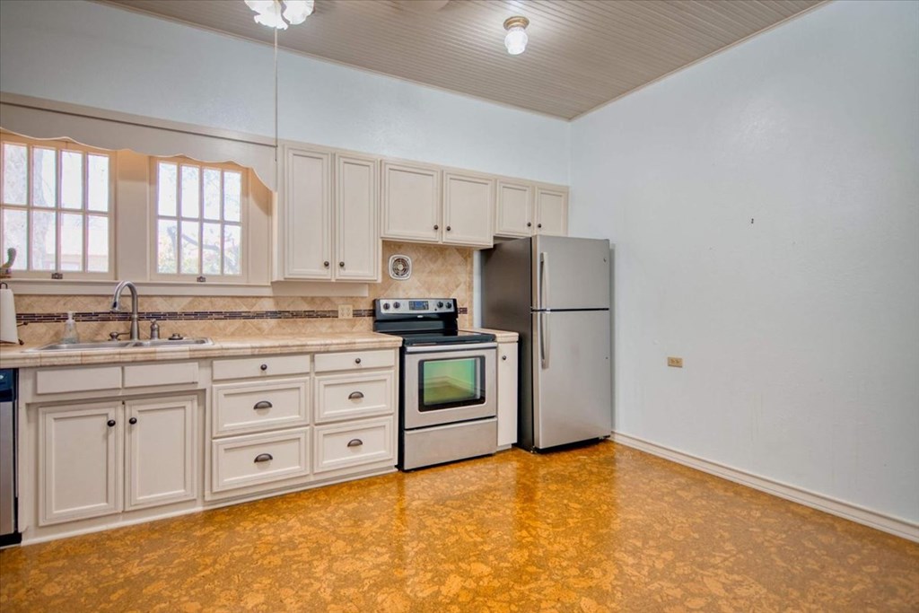 205 East Rainey Street Mason, TX 76856 - Photo 11 of 37 a kitchen with granite countertop white cabinets and stainless steel appliances