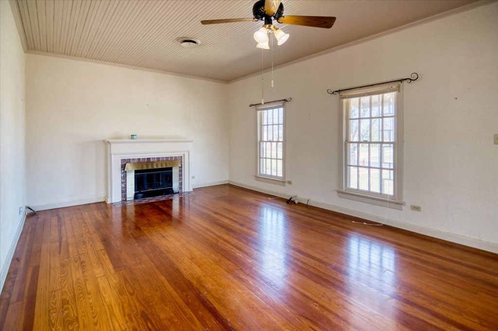 205 East Rainey Street Mason, TX 76856 - Photo 3 of 37 a view of an empty room with wooden floor fireplace and a window