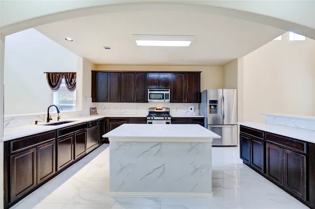 a kitchen with stainless steel appliances a sink dishwasher stove refrigerator and cabinets