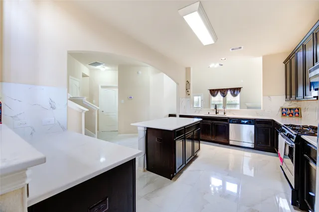 a kitchen with stainless steel appliances granite countertop a stove a sink and a refrigerator