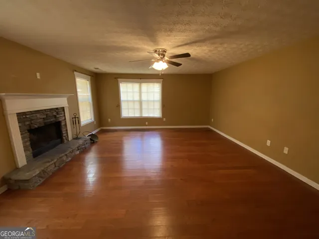 an empty room with windows and fireplace