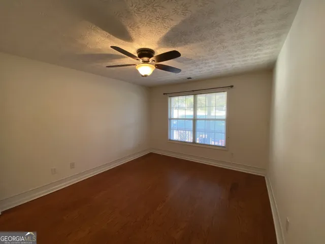 an empty room with a window and a fan