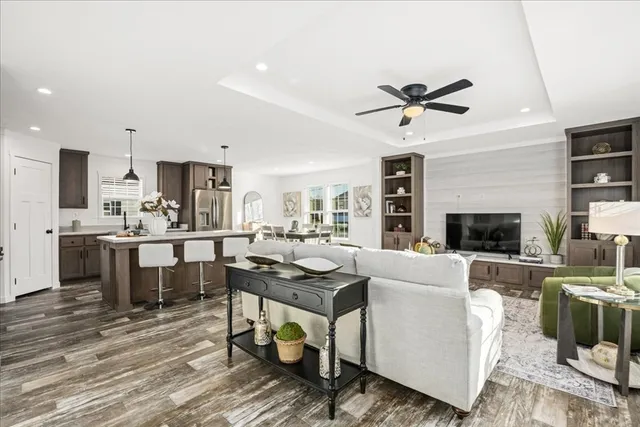 a living room with stainless steel appliances kitchen island granite countertop furniture a fireplace wooden floor and a rug