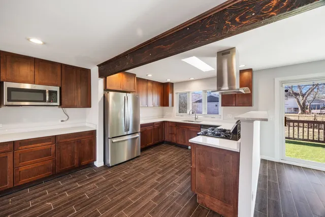 a kitchen with stainless steel appliances granite countertop a refrigerator a stove top oven a sink dishwasher and wooden cabinets with wooden floor