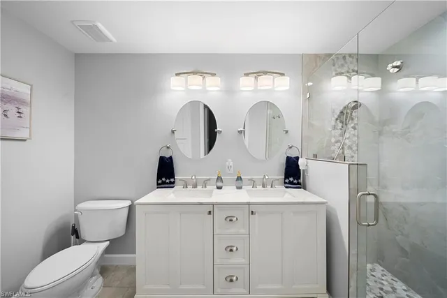 a bathroom with a double vanity sink mirror and toilet