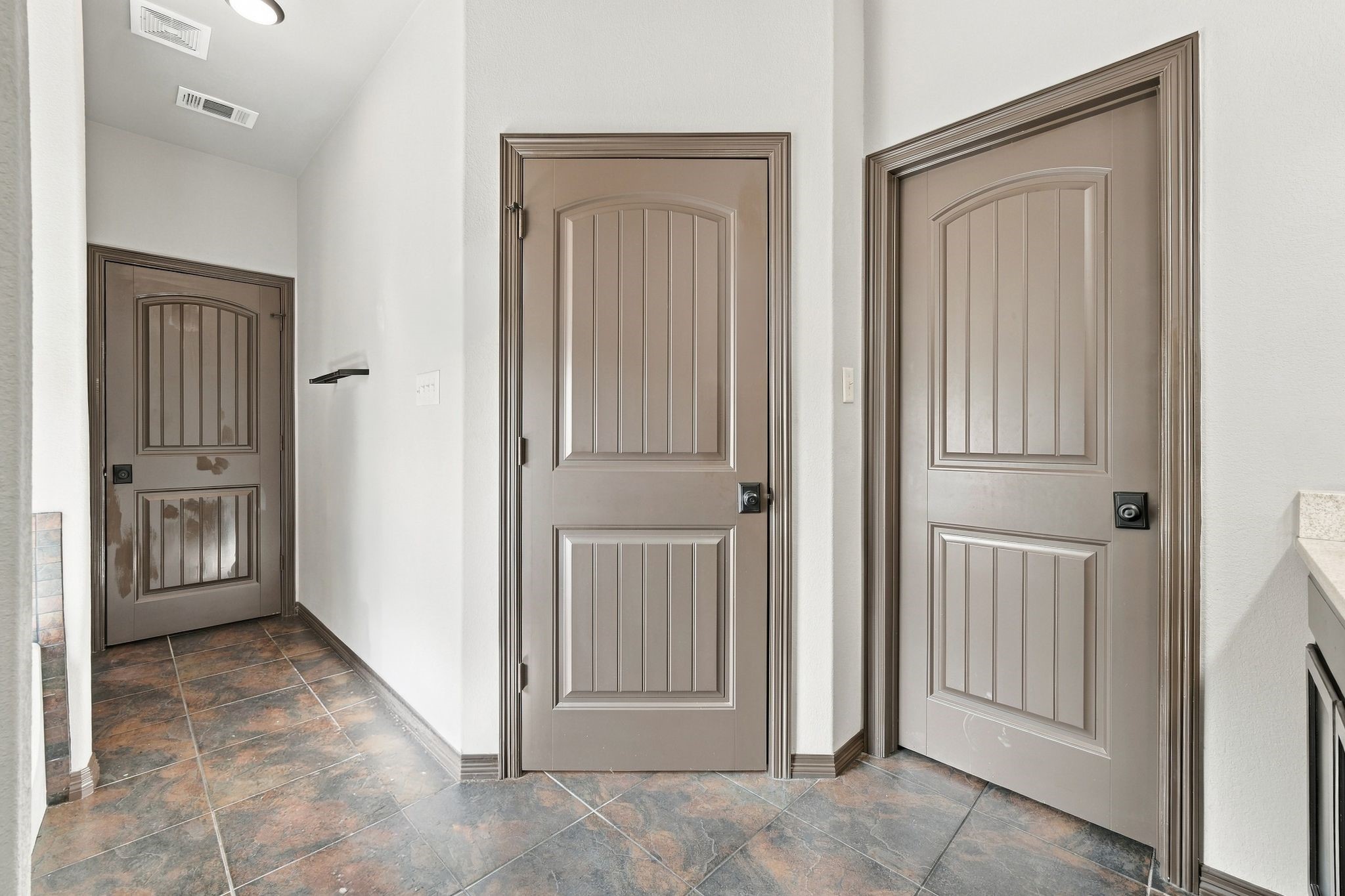 7049 Pine Shadows Road Cleveland, TX 77328 - Photo 21 of 49 Hallway with elegant, paneled doors and stylish tile flooring, offering a sophisticated entry to the home’s interior spaces.