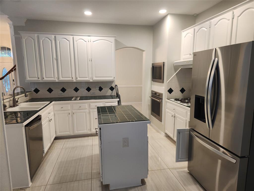 4175 Midrose Trail Dallas, TX 75287 - Photo 5 of 14 Kitchen featuring white cabinetry with arch panel doors, a tiled backsplash with diamond accents, and an island with a tiled countertop
