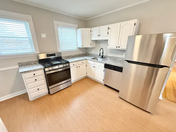 a kitchen with stainless steel appliances a refrigerator sink and white cabinets