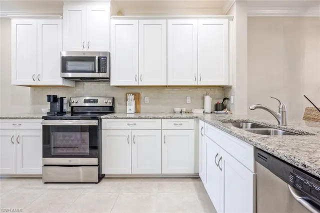a kitchen with granite countertop white cabinets and stainless steel appliances