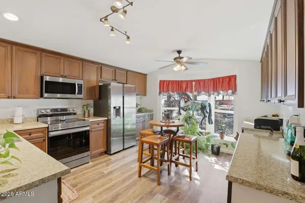 a kitchen with stainless steel appliances granite countertop a stove top oven a refrigerator a sink dishwasher a dining table and chairs with wooden floor