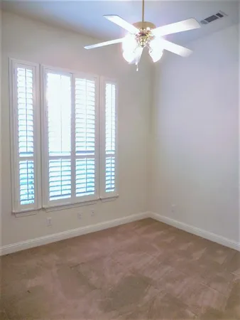 an empty room with a window and a fan