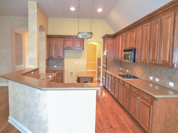 a kitchen with kitchen island granite countertop a sink a counter top space and cabinets