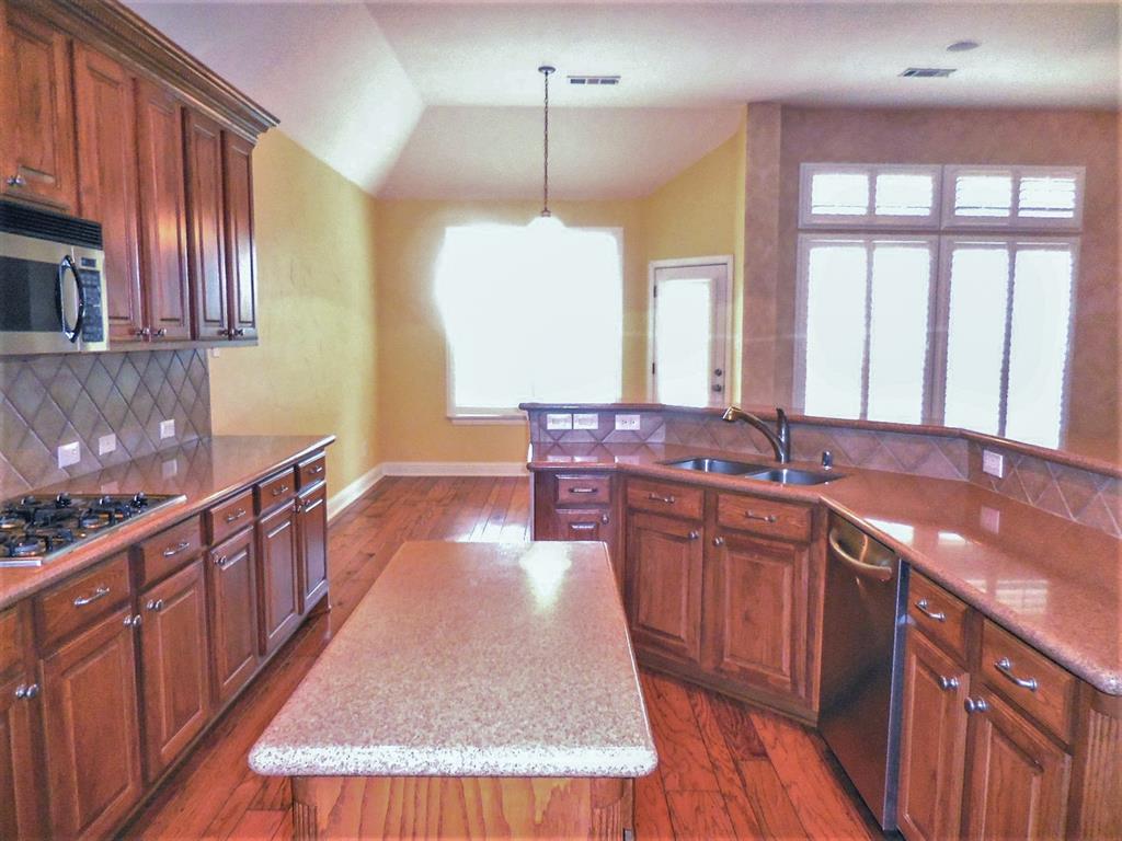 4012 Appleton Lane Flower Mound, TX 75022 - Photo 10 of 28 a large kitchen with kitchen island granite countertop a sink stove and wooden cabinets