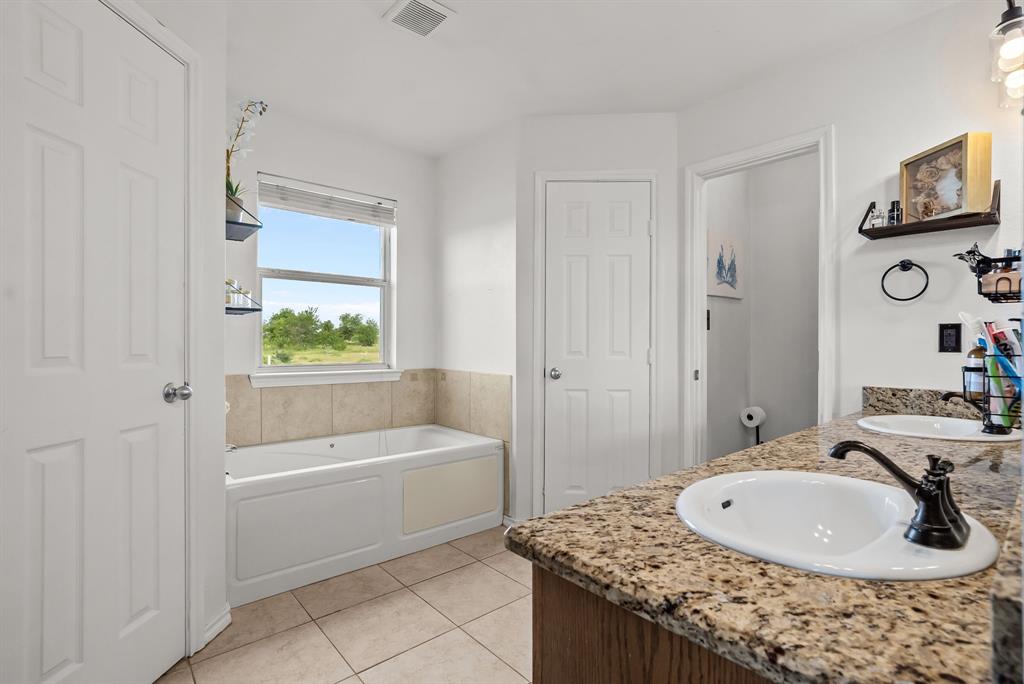 115 Blue Castle Court Weatherford, TX 76088 - Photo 15 of 33 a bathroom with a granite countertop sink a toilet and bathtub