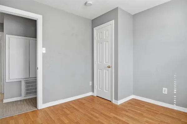 a view of an empty room with wooden floor and closet