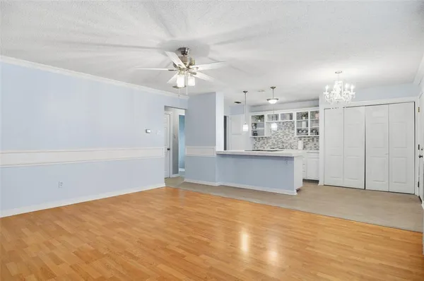 an empty room with chandelier fan and windows