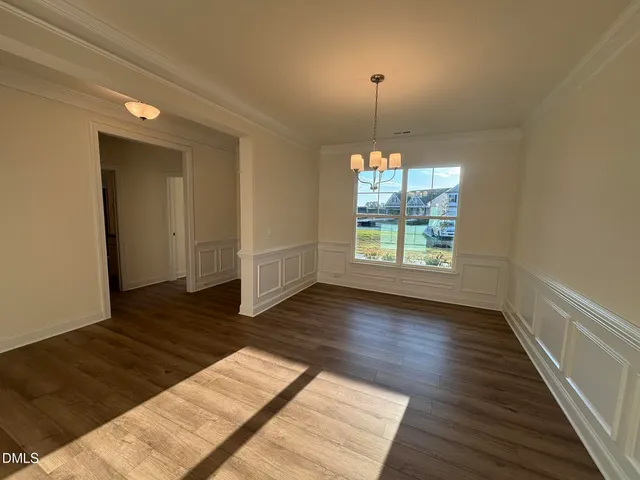 an empty room with wooden floor chandelier and windows