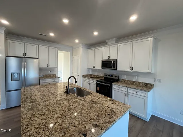 a kitchen with granite countertop a stove sink and refrigerator