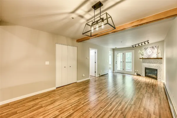 a view of an empty room with wooden floor fireplace and a window