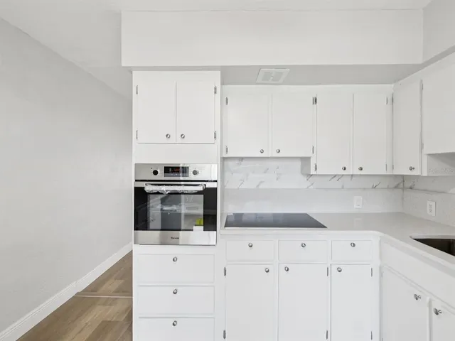 a kitchen with granite countertop white cabinets and stainless steel appliances
