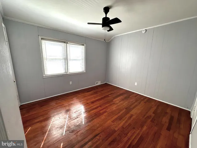 a view of empty room with wooden floor and fan