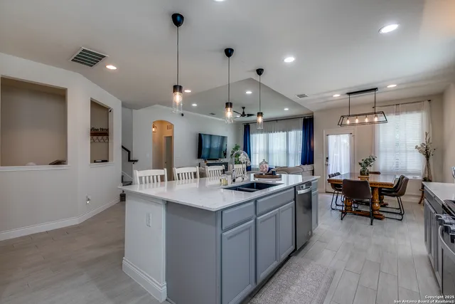 a large kitchen with kitchen island a sink a stove a dining table and chairs