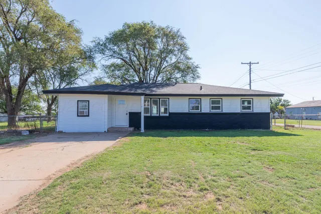 a front view of house with yard and trees in the background