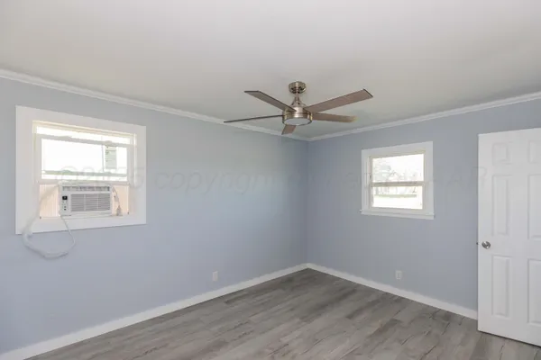 a view of a big room with wooden floor and windows