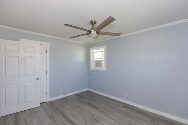 an empty room with wooden floor and ceiling fan