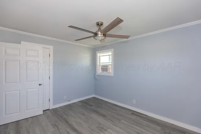an empty room with wooden floor and ceiling fan
