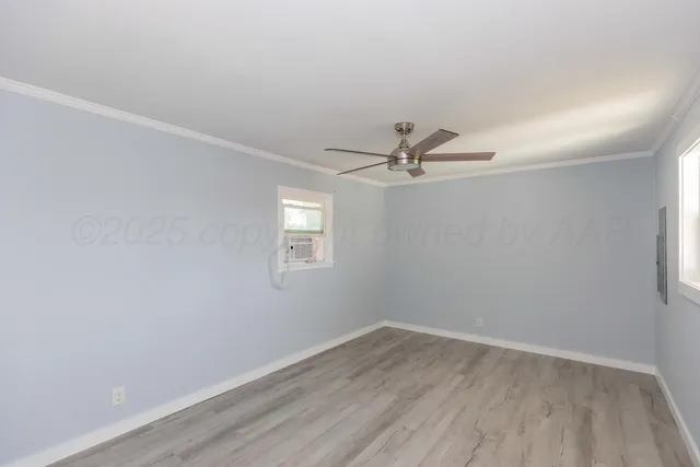 an empty room with wooden floor fan and windows