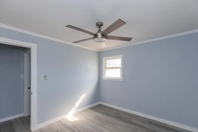 a view of a livingroom with a window a ceiling fan and wooden floor