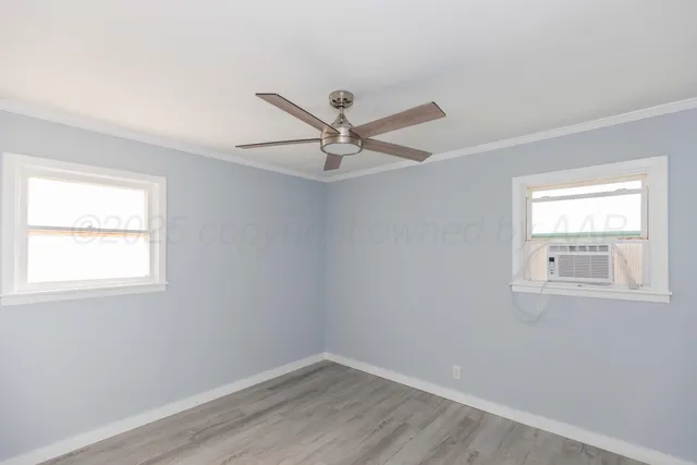 an empty room with wooden floor fan and windows