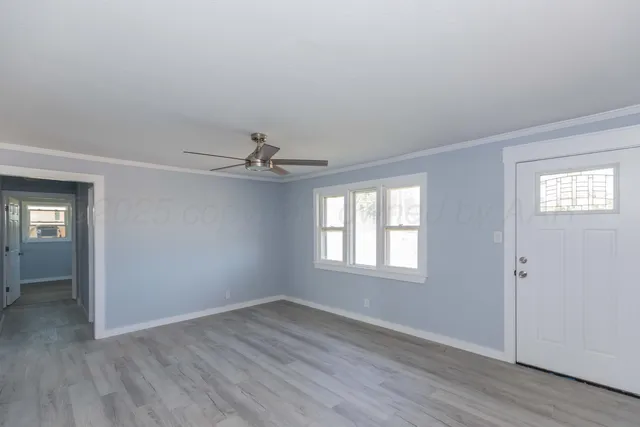 an empty room with wooden floor chandelier fan and windows