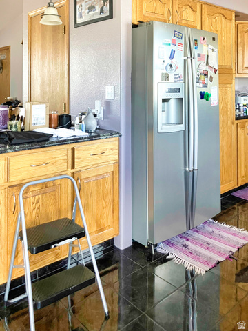 1060 Freedom Way Kanab, UT 84741 - Photo 4 of 12 Kitchen with stainless steel fridge, a textured wall, granite tiled floors, and dark stone counters